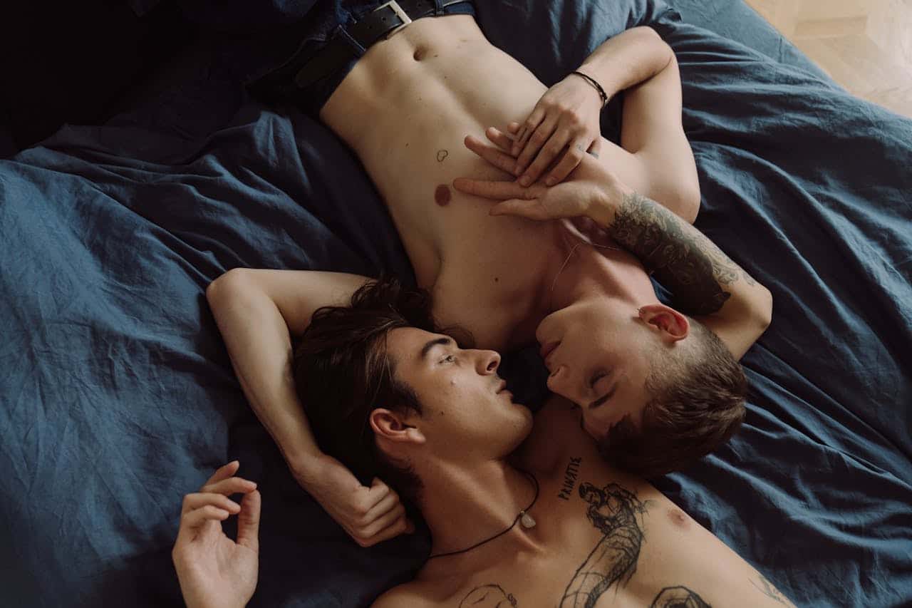 Two men sharing an intimate moment, embracing on a bed, expressing love and connection.