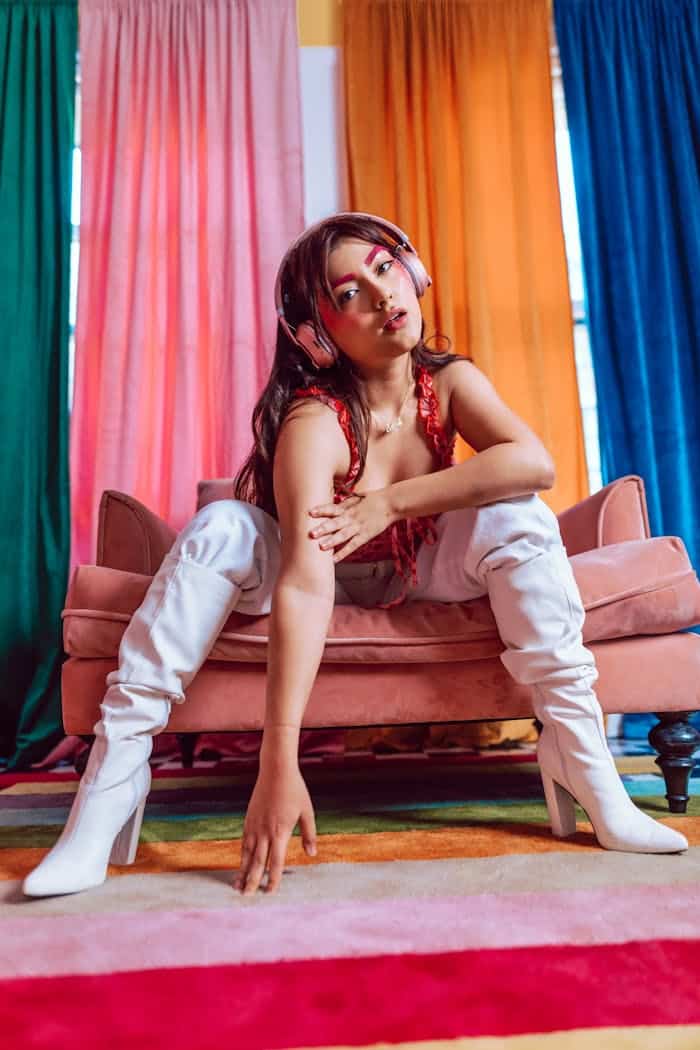 Colorful portrait of a stylish person indoors with eclectic fashion and vibrant curtains.